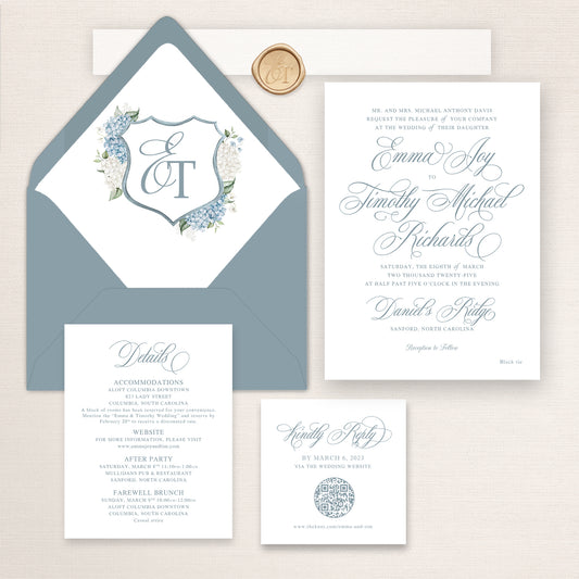 Dusty blue script wedding invitation suite with elegant calligraphy typography, QR RSVP card, details insert, wax seal, and matching blue envelopes with a crest liner.