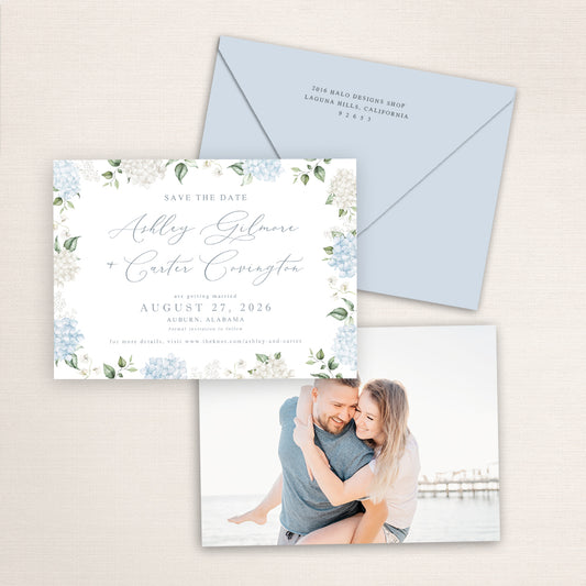 Blue hydrangea floral save the date card paired with a soft blue envelope and coordinating photo back of a smiling couple on the beach, creating a cohesive and romantic wedding stationery suite.
