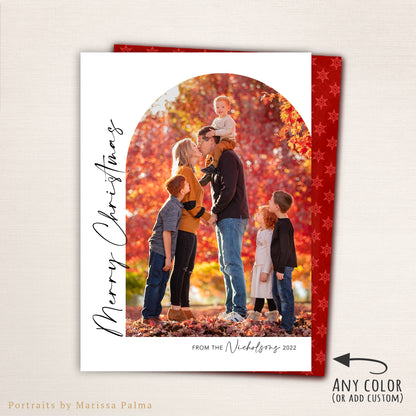 “Merry Christmas” photo card from Halo Design Shop featuring a modern arched photo layout with vertical script text, personalized family name, and a festive red snowflake-patterned back. Fully customizable colors and fonts make this elegant holiday card perfect for sharing family memories.
