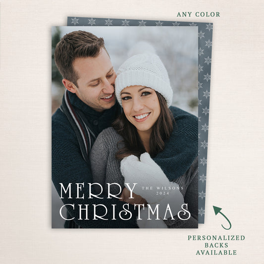 “Merry Christmas” modern holiday photo card from Halo Design Shop featuring a vertical full-photo layout with elegant serif typography, personalized family name, and customizable back design.