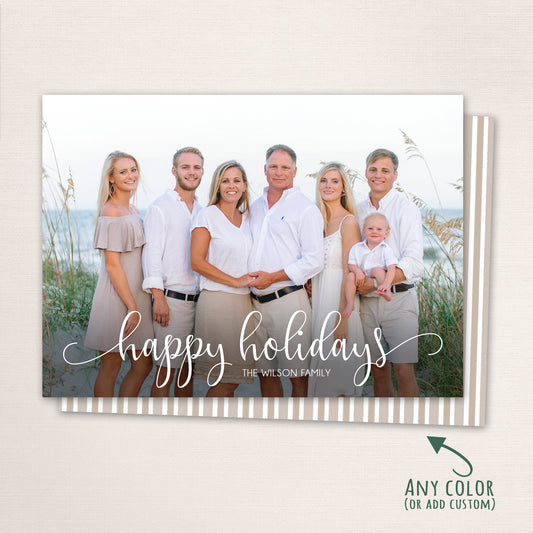 Elegant coastal holiday card with “Happy Holidays” written in modern white script across a family portrait taken by the ocean. The design features neutral tones, soft lighting, and an optional striped back in coordinating colors.