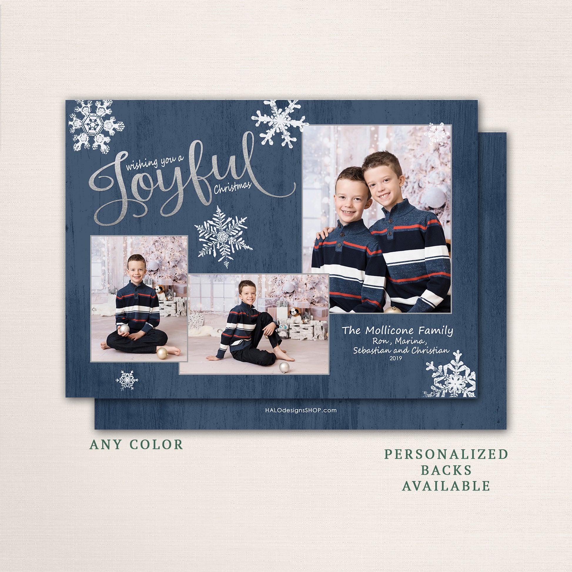 Two young brothers in navy and red sweaters posing in front of a soft winter-themed backdrop with “Wishing You a Joyful Christmas” in silver script over a navy wood background.