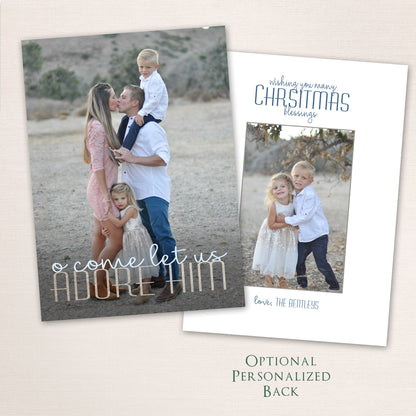 Faith-inspired Christmas photo card featuring a family of four in a natural outdoor setting. The design includes the words “O Come Let Us Adore Him” in elegant mixed script and block lettering, with an optional personalized back for extra photos or text.