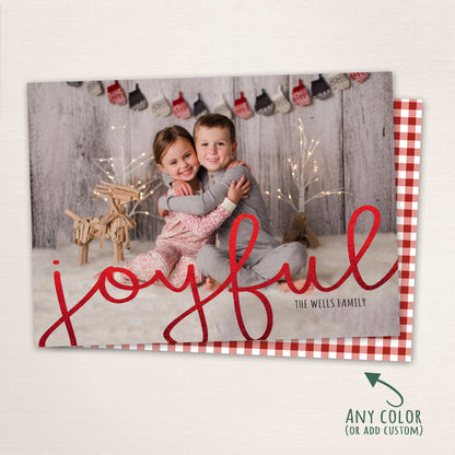Siblings in pajamas hugging each other with “Joyful” written in a matching red script across the photo, with a red plaid background.