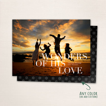 Horizontal Christmas photo card featuring a family sitting outdoors with large white text reading “wonders of His love” customizable with family name and holiday message.