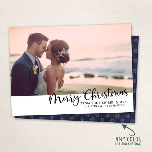 Newlywed couple embracing on the beach at sunset with “Merry Christmas” in modern black script and customizable background color.