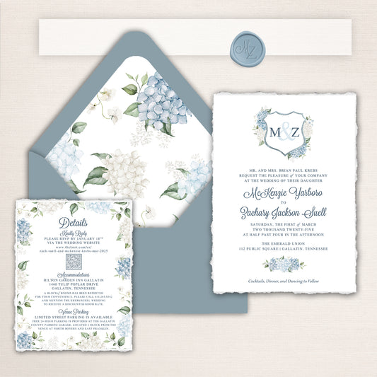 Wedding invitation suite with deckle edges. Design features Dusty blue and white hydrangeas, a custom crest, and matching Blue envelopes, liners, and wax seal.