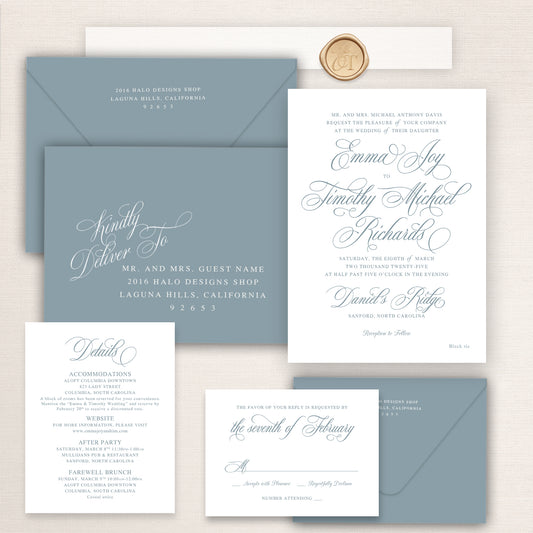 Dusty blue script wedding invitation suite with elegant calligraphy typography, RSVP card, details insert, wax seal, and matching blue envelopes.