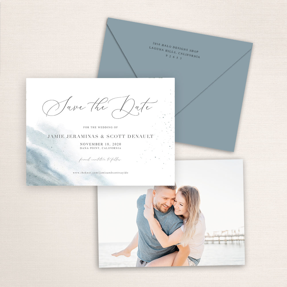 Dusty blue watercolor save the date suite featuring a romantic beach-inspired design with modern calligraphy and a coordinating blue envelope. The card is paired with a photo back of a couple embracing on the beach.