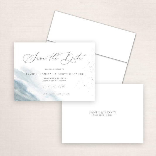 Elegant dusty blue watercolor save the date card with flowing calligraphy reading “Save the Date” and wedding details. The design includes a soft watercolor wash on the left and minimalist text on white background.