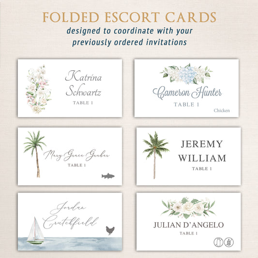 Set of folded watercolor escort cards with assorted floral, coastal, and botanical designs. Each card features guest names, table numbers, and optional meal icons to coordinate with wedding stationery suites.