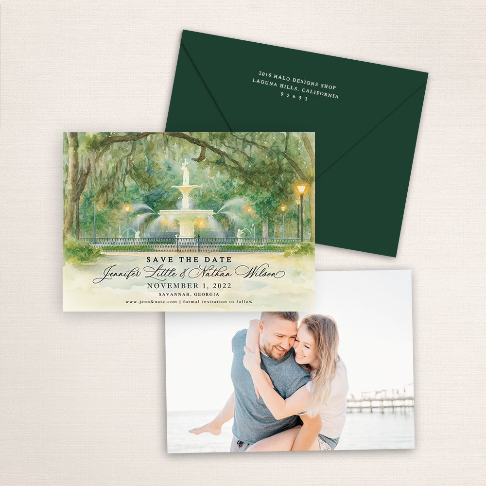 Forsyth Park Fountain Savannah save the date featuring a soft watercolor painting of the historic fountain under oak trees with glowing lanterns, elegant script names, dark green envelope, and engagement photo on the back.