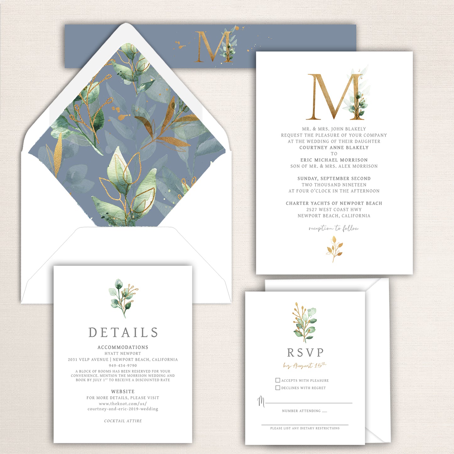 Gold monogram wedding invitation suite with watercolor greenery and soft blue accents, including invitation, RSVP, and detail cards with matching botanical envelope liner and monogram belly band.