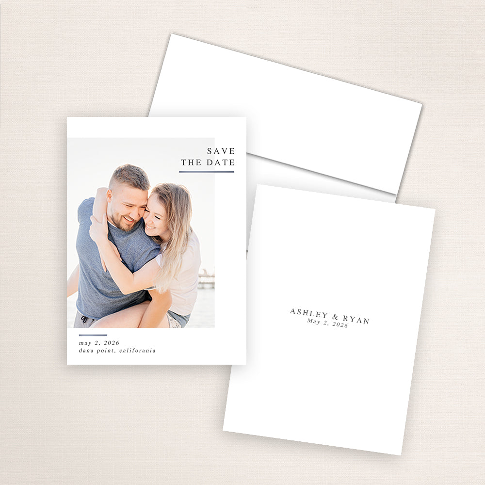 Modern minimalist photo save the date card featuring a couple embracing at the beach with natural sunlight. The design includes classic serif text reading “Save the Date” in the upper right corner with wedding details for Ashley and Ryan below.