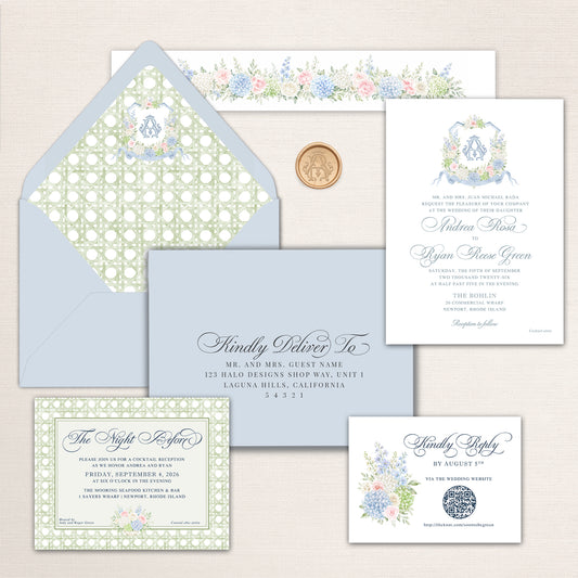 Elegant coastal wedding invitation suite with soft blue, sage green, ivory, blush pink, and hydrangea blue. The suite features a pale blue envelope with a watercolor green rattan-pattern liner and floral monogram crest, a coordinating gold monogram wax seal, and a formal white wedding invitation with delicate blue calligraphy and a watercolor floral crest. Coordinating pieces include an addressed envelope, a floral-lined belly band, a rattan-bordered reception card, and RSVP with QR code.